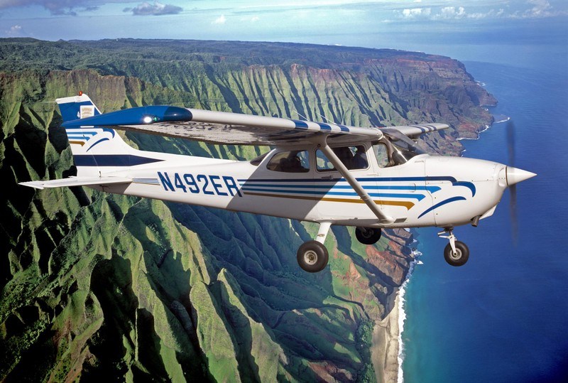 Cessna airplane flying beside Kauai’s Na Pali coastline